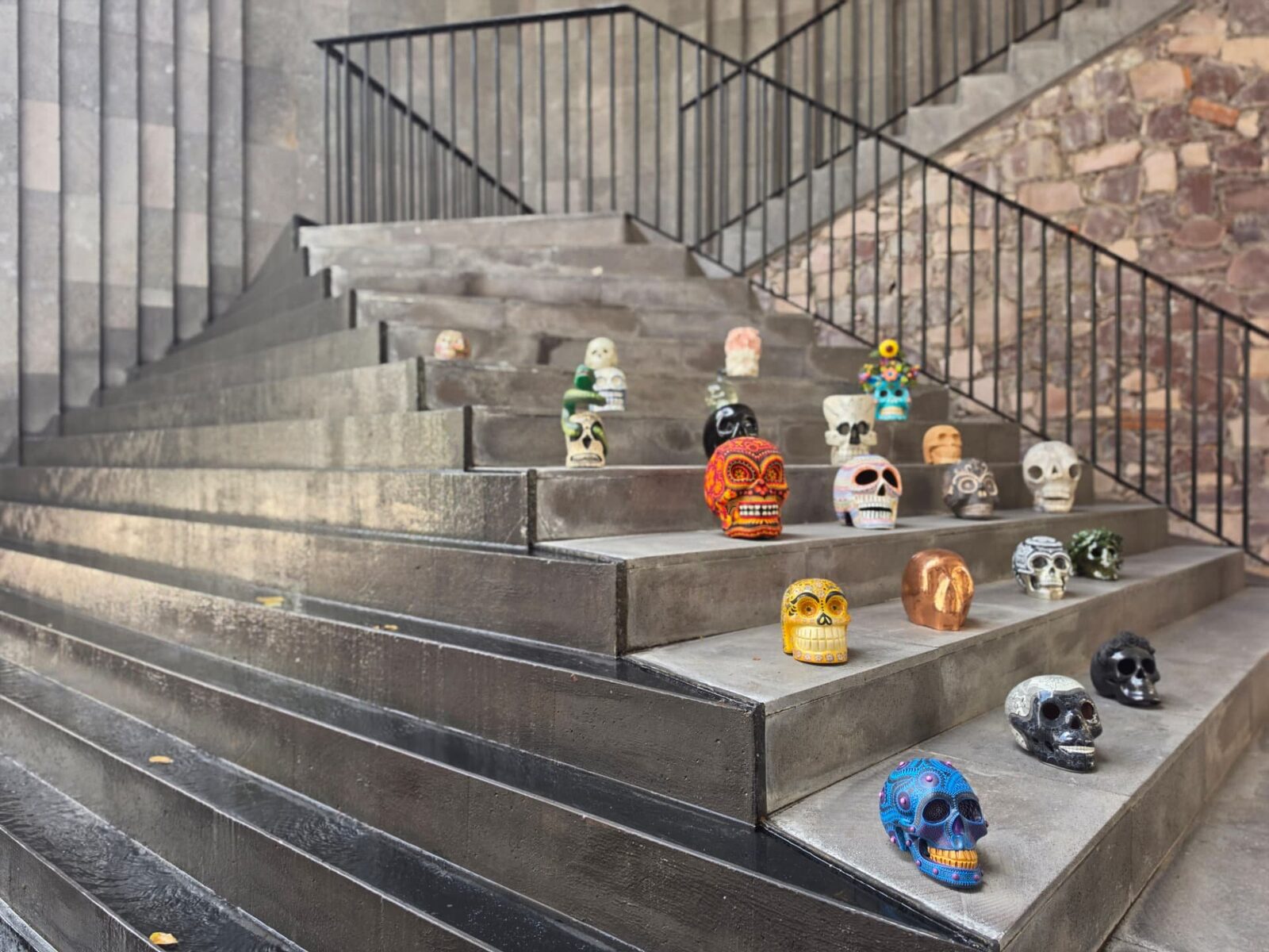 Cráneos de arte popular expuestos en las escaleras del Tzompantli Collection 2026